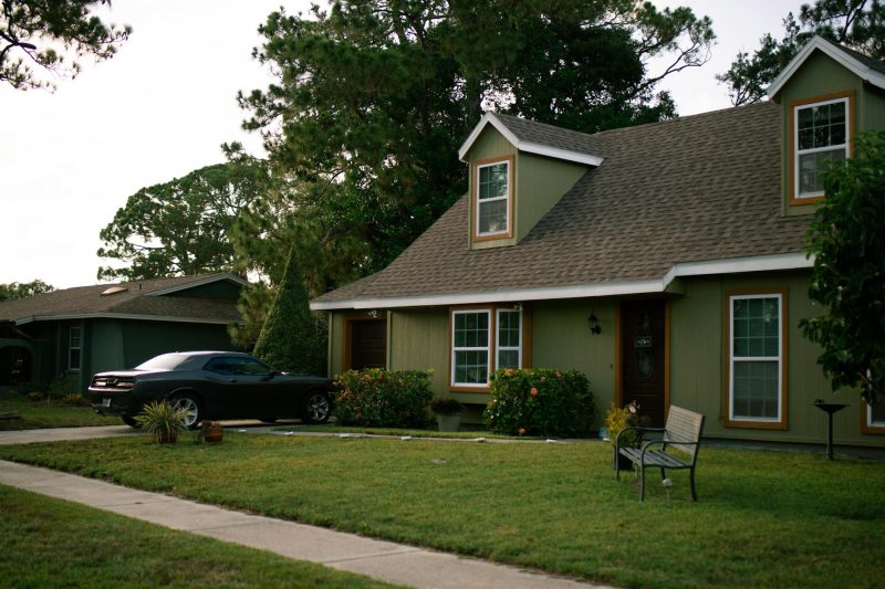 A charming suburban home with a neat green lawn and a parked car, reflecting residential comfort.