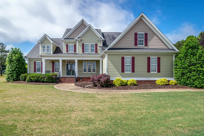 Two-story suburban house with a manicured lawn and a welcoming front porch.