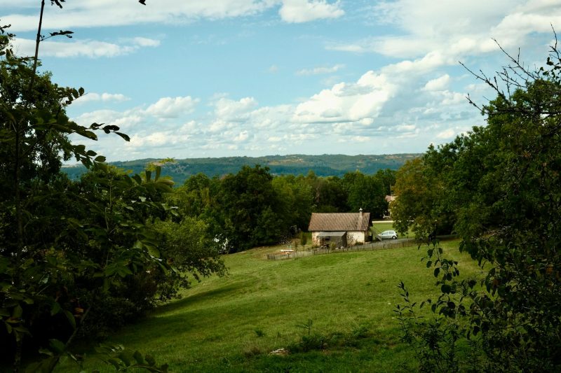 Scenic farmhouse surrounded by green fields and trees in the countryside.