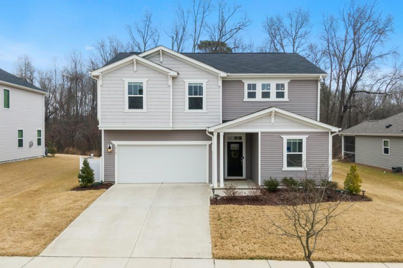 Charming two-story suburban home with a garage, surrounded by greenery in a residential neighborhood.