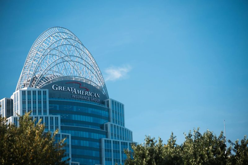 Modern Great American Tower skyscraper with an arch top, surrounded by greenery against a clear blue sky.