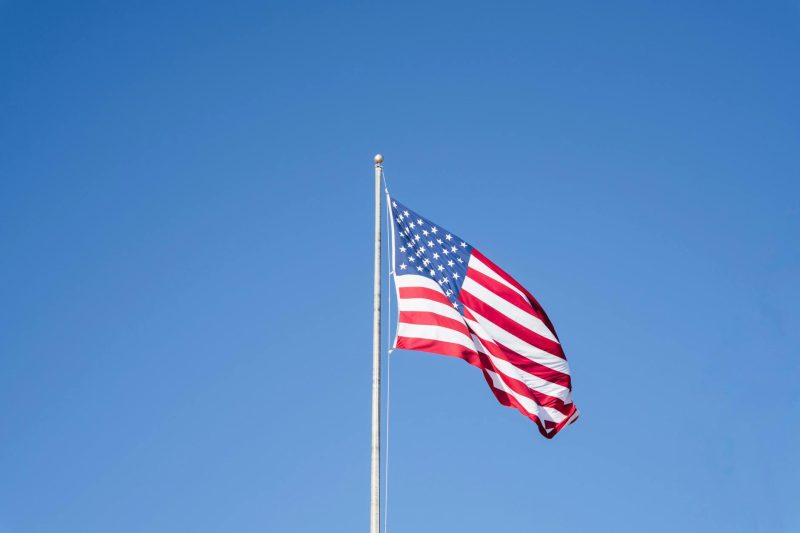 A vibrant American flag waves against a bright blue sky, symbolizing patriotism and freedom.