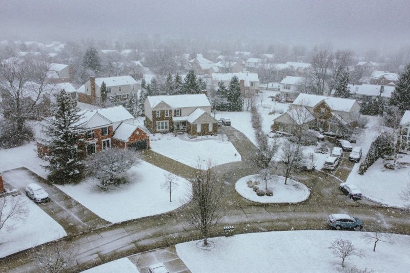 Aerial view of a snow-covered suburban neighborhood with quiet streets and houses.