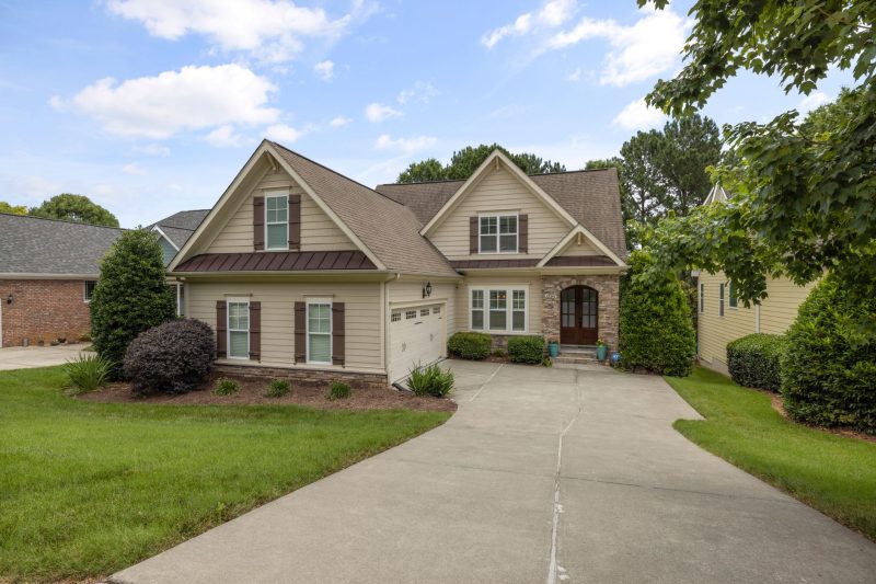 Beautiful suburban family home with a well-maintained lawn and driveway, surrounded by trees.