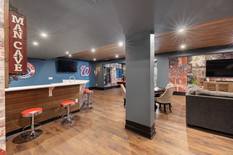 Modern man cave featuring a sleek bar, sports decor, and comfortable seating.