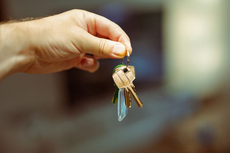 A hand holds a keyring with multiple house keys, highlighting home ownership.